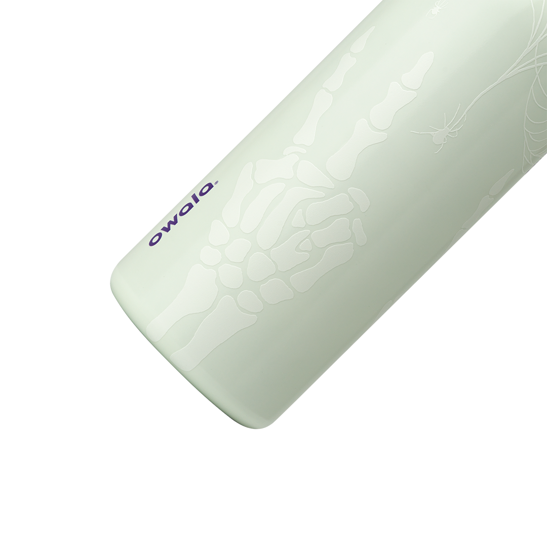 Owala FreeSip 32oz in RIP, close-up of pale mint insulated stainless steel body with white skeleton hand, spider web, and spider glow print, dark purple owala wordmark; glows in the dark