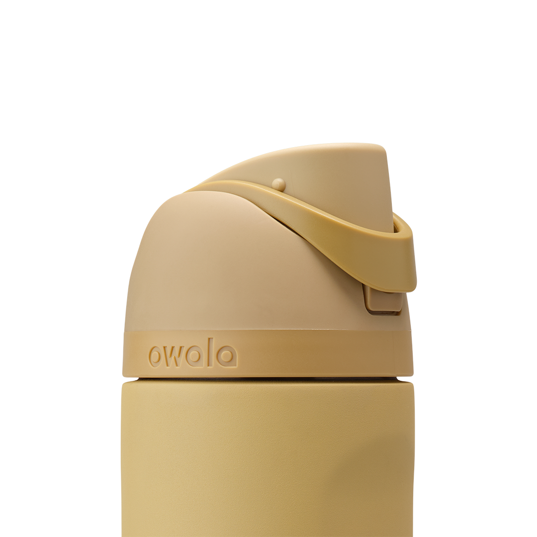 Owala FreeSip 24oz in Autumn Vista, close-up of warm honey-sand lid with matching carry loop in closed position